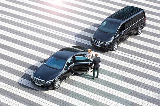 Ein Chauffeur hilft einer Frau beim Einsteigen in eine Limousine.